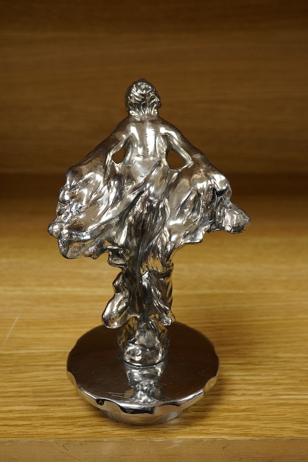 A Sykes style chromed car mascot in the form of an Art Deco woman with flowing gown, indistinctly signed to the base and dated 1922, mounted on a threaded radiator cap. Condition - fair to good.